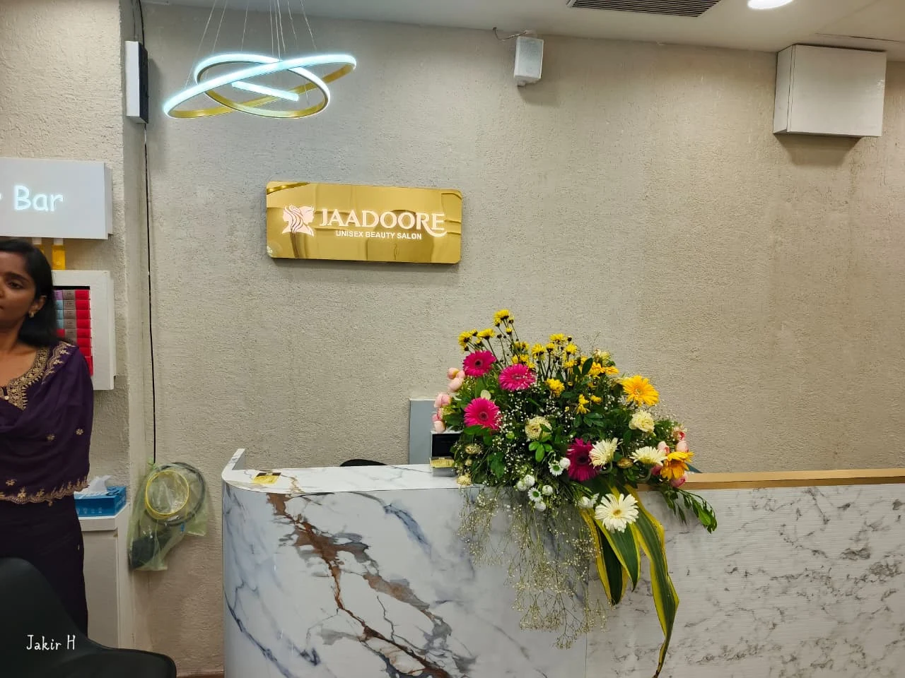 White marble reception desk with fresh flowers and gold Jaadoore lettering