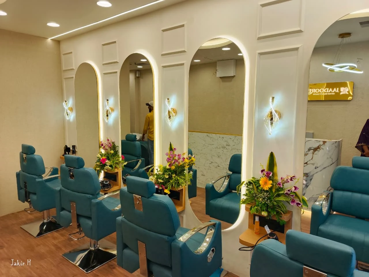 Row of illuminated oval mirrors with teal styling chairs